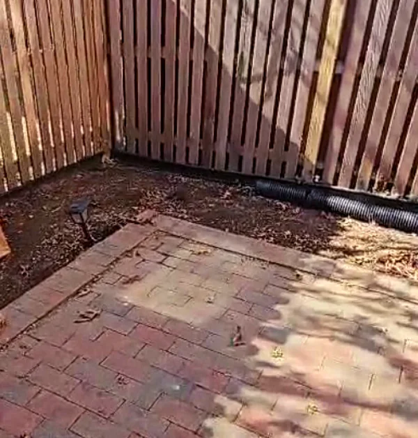 Existing brick paver patio showing uneven settling and low areas near the rear porch and stair landing before renovation.