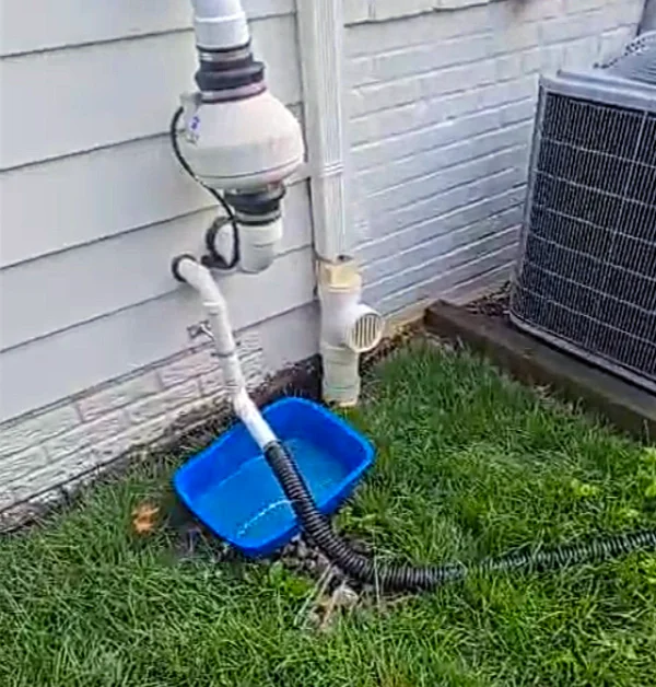 Existing sump pump discharge pipe releasing large amounts of water near the home's foundation, causing saturated soil and pooling during heavy rainfall.