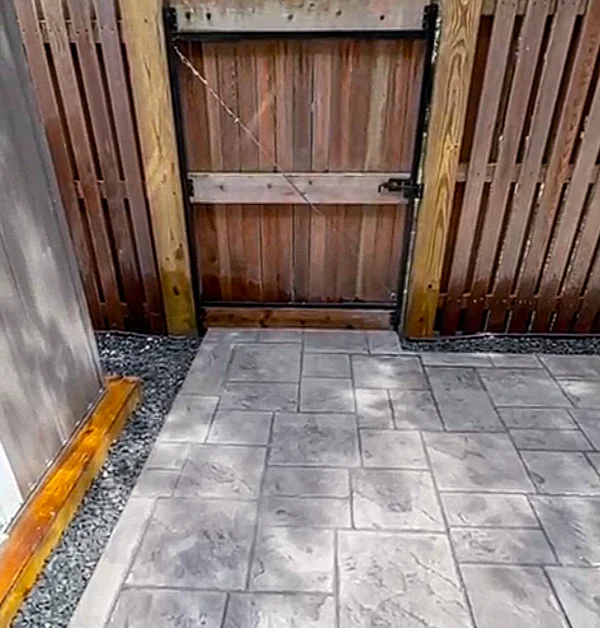 Rear gate area after renovation with stamped concrete replacing the old brick patio and a cleaner transition to the backyard entrance.