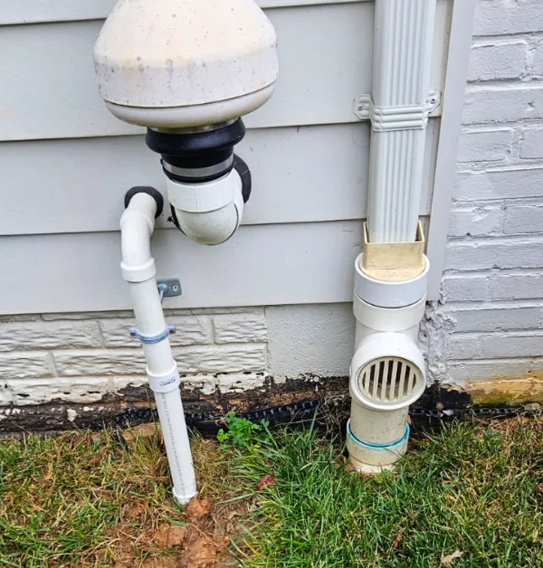 Completed underground sump pump drainage installation in Kensington, MD, showing the restored lawn, buried PVC discharge route, and drainage path extending away from the home's foundation.