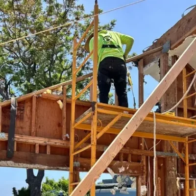 Two construction workers are on scaffolding, working on a house renovation.