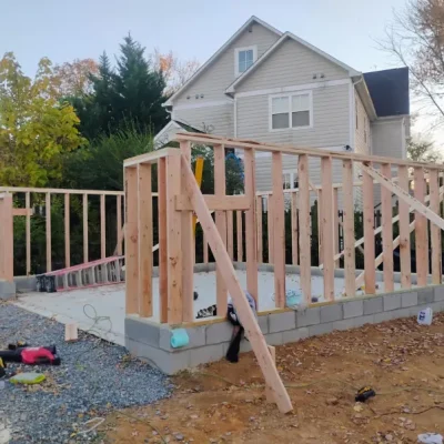Wooden frame of a new structure under construction in front of a house.