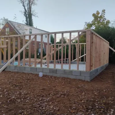 Wooden frame structure under construction on a concrete block foundation.