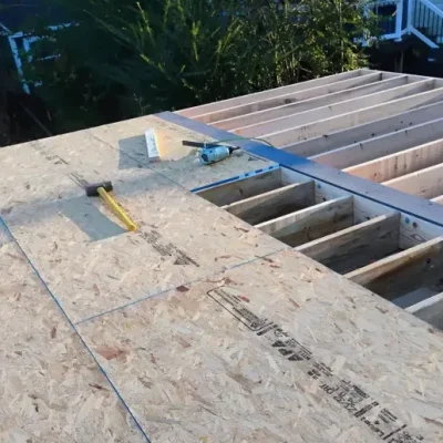 Partially completed roof with plywood sheets, tools, and visible wooden beams.