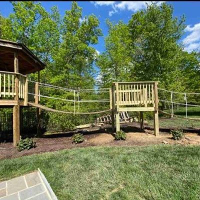Backyard treehouse with rope bridge.